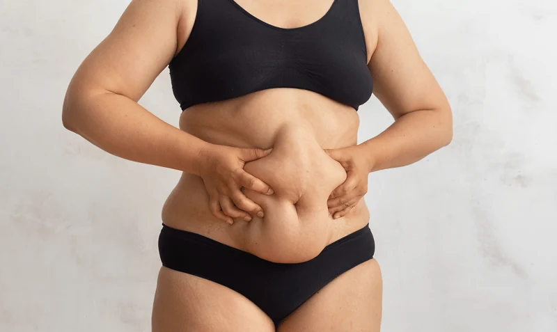 Person holding their midsection, representing common body confidence concerns